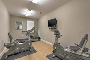 Interior Fitness Center, two stationary bikes, treadmill, tile floor, neutral toned walls, tv in fitness center.
