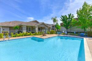 Exterior Community Pool, 2 chaise lounge chairs, palm tree planted in pool area, gated pool, two four seat picnic tables.